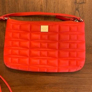 Orange skate spade clutch with strap.